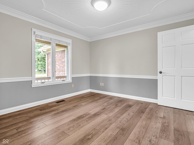 spare room with visible vents, baseboards, wood finished floors, and ornamental molding