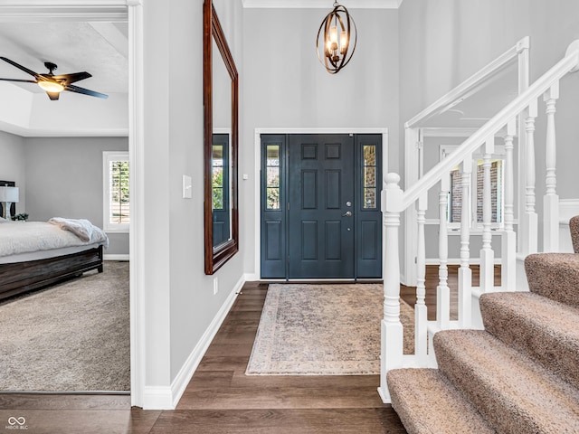 entryway featuring stairway, baseboards, dark wood-style floors, and ceiling fan with notable chandelier