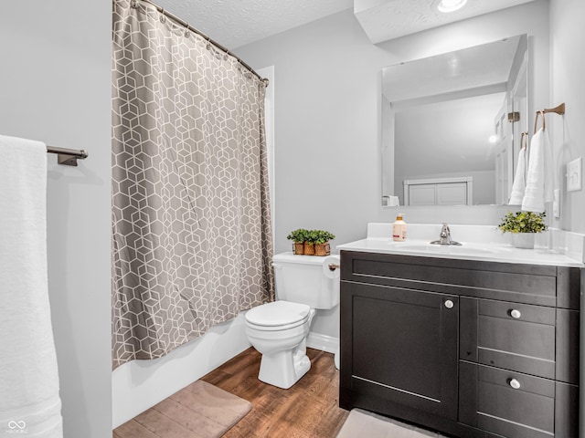 bathroom with toilet, vanity, wood finished floors, a textured ceiling, and shower / bathtub combination with curtain