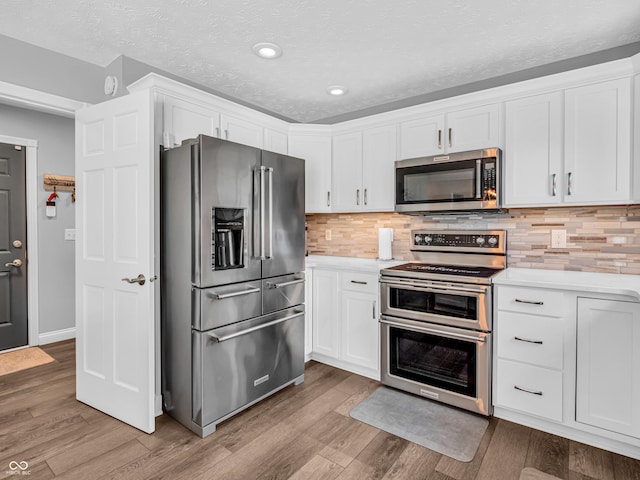 kitchen with light countertops, wood finished floors, tasteful backsplash, and stainless steel appliances