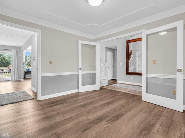 empty room with french doors, baseboards, wood finished floors, and ornamental molding