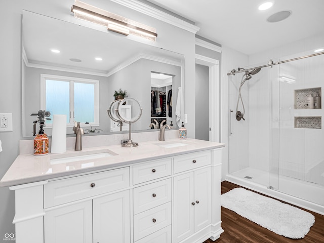 full bathroom with double vanity, a shower stall, wood finished floors, and a sink