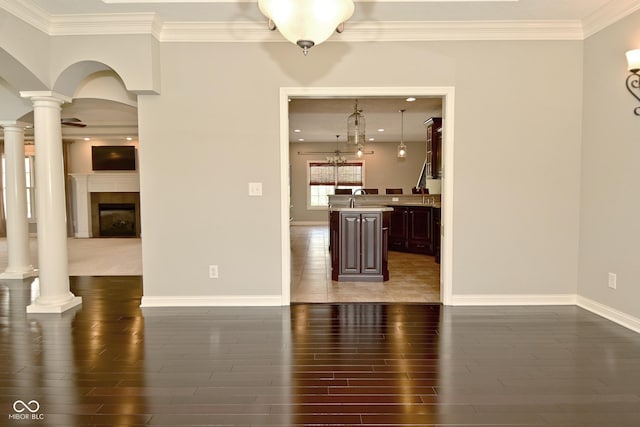 interior space featuring ornamental molding, decorative columns, and wood finished floors