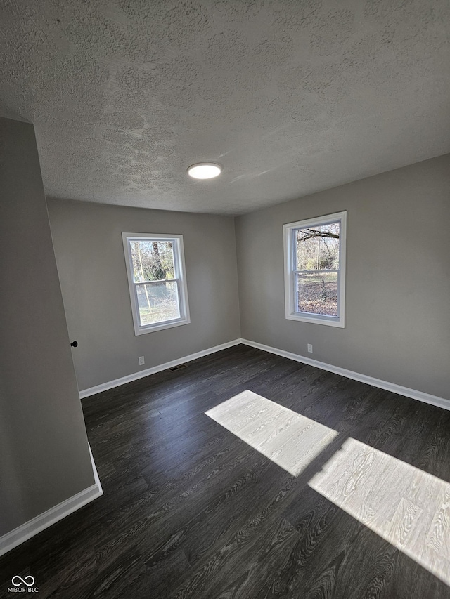 unfurnished room featuring baseboards, a textured ceiling, and dark wood finished floors