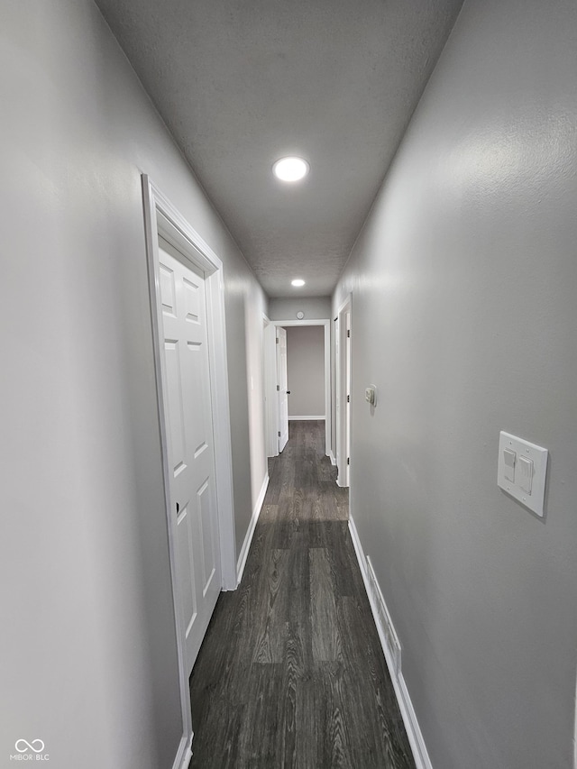 hallway featuring dark wood-style floors and baseboards