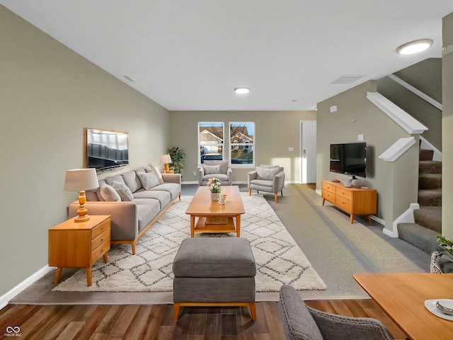 living area featuring visible vents, baseboards, wood finished floors, and stairs