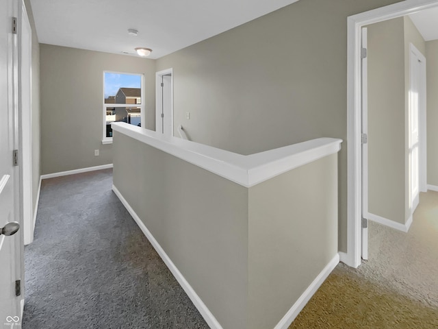 corridor with an upstairs landing, carpet flooring, and baseboards