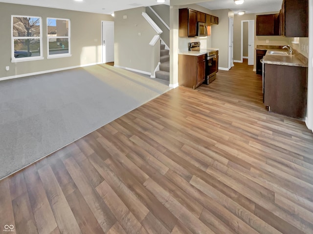 kitchen with light wood-style flooring, a sink, light countertops, appliances with stainless steel finishes, and open floor plan