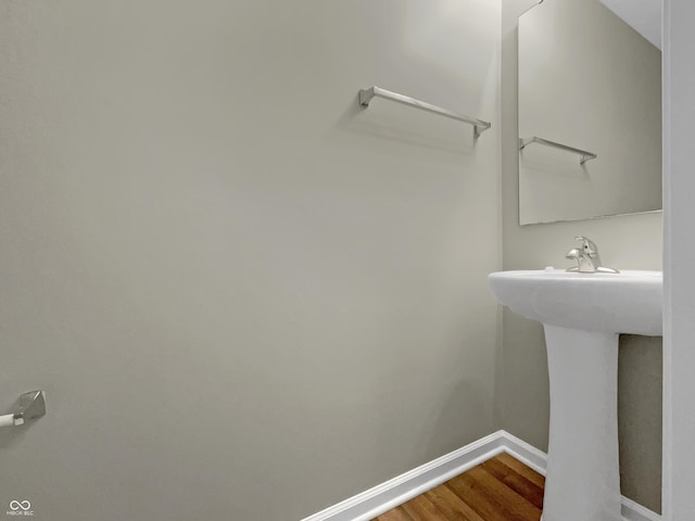 bathroom with a sink, baseboards, and wood finished floors