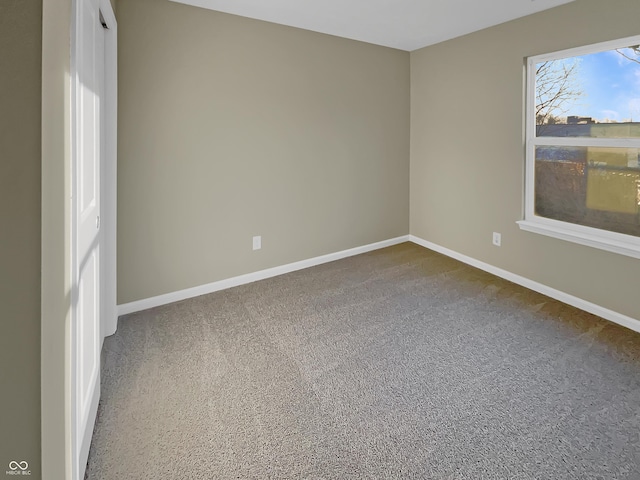 carpeted empty room featuring baseboards