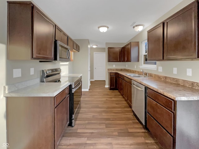 kitchen with a sink, appliances with stainless steel finishes, light wood-style flooring, and light countertops