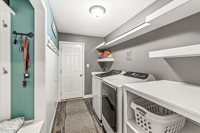 laundry area featuring baseboards, dark wood finished floors, laundry area, a textured ceiling, and washer and dryer