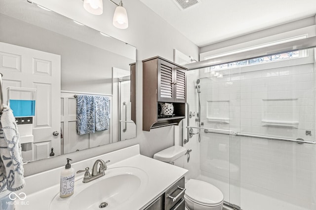 bathroom featuring visible vents, a shower stall, toilet, and vanity