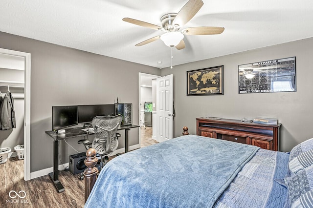 bedroom featuring baseboards, wood finished floors, and a ceiling fan