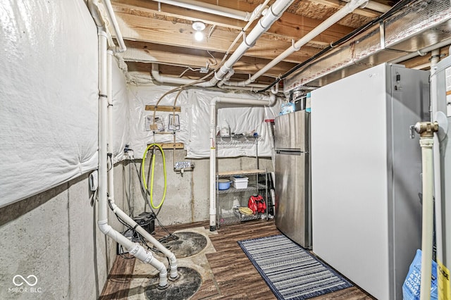 unfinished basement featuring freestanding refrigerator and wood finished floors