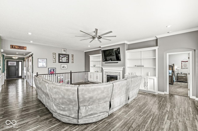 living room featuring dark wood-type flooring, ornamental molding, a fireplace, and ceiling fan