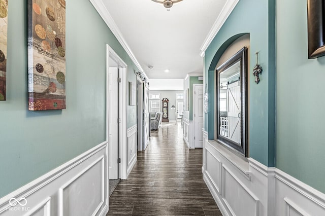 corridor featuring a decorative wall, dark wood-type flooring, a wainscoted wall, and ornamental molding