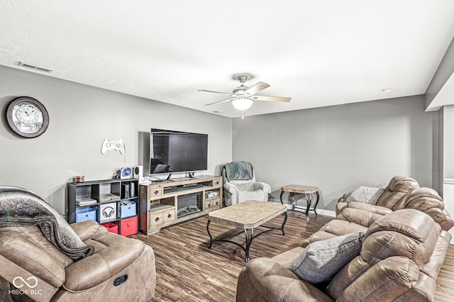 living room featuring visible vents, baseboards, ceiling fan, and wood finished floors