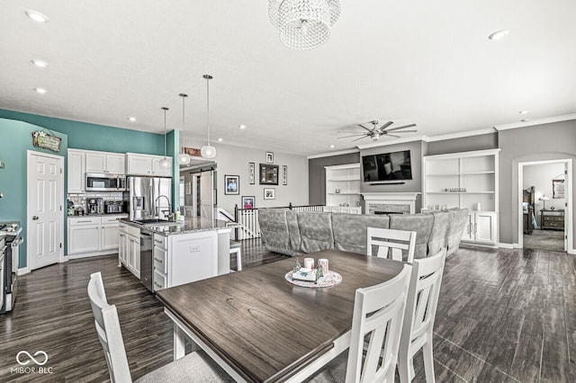 dining room featuring a fireplace, recessed lighting, ornamental molding, ceiling fan, and dark wood-type flooring