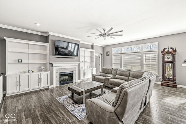 living room featuring ornamental molding, a ceiling fan, dark wood finished floors, a fireplace, and baseboards