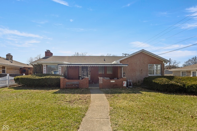 view of front of home featuring brick siding, a chimney, a front lawn, and fence