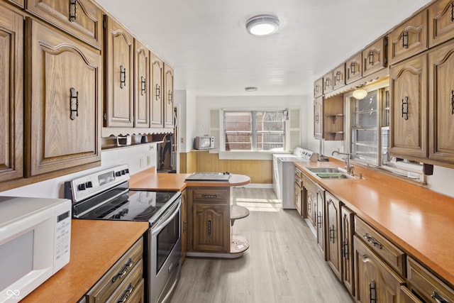 kitchen with light wood-style flooring, electric stove, a sink, white microwave, and washer / dryer