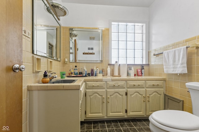 bathroom featuring tile patterned flooring, tile walls, toilet, and vanity