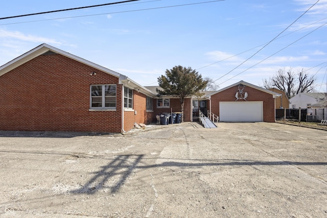 view of front facade with concrete driveway, an attached garage, fence, and brick siding