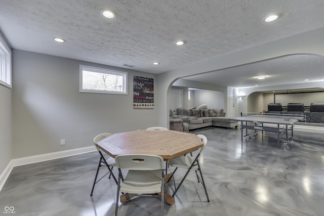 dining area with baseboards, arched walkways, concrete floors, and a textured ceiling