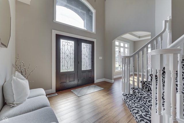 entrance foyer with visible vents, baseboards, stairway, wood finished floors, and arched walkways