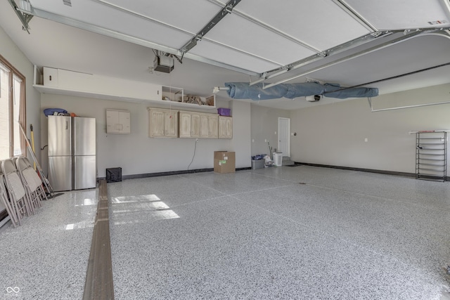 garage featuring a garage door opener, baseboards, and freestanding refrigerator