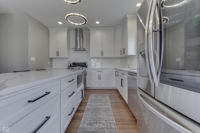 kitchen featuring backsplash, white cabinets, stainless steel appliances, and wall chimney exhaust hood