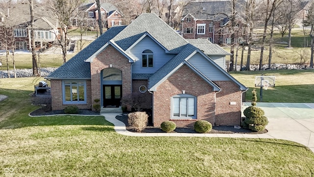 view of front of house featuring a front yard, brick siding, driveway, and a shingled roof