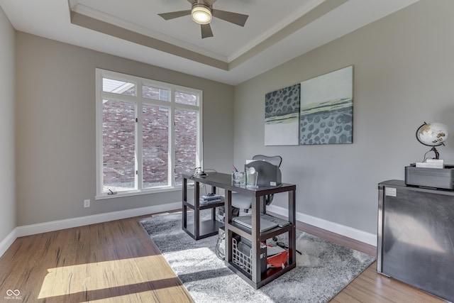 office area featuring a raised ceiling, wood finished floors, and a ceiling fan