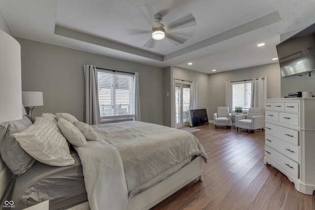 bedroom with recessed lighting, a ceiling fan, a tray ceiling, and wood finished floors