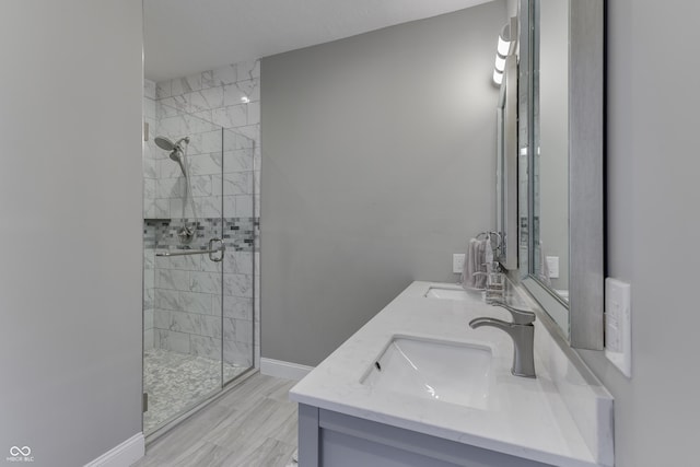 bathroom with double vanity, a shower stall, baseboards, and a sink