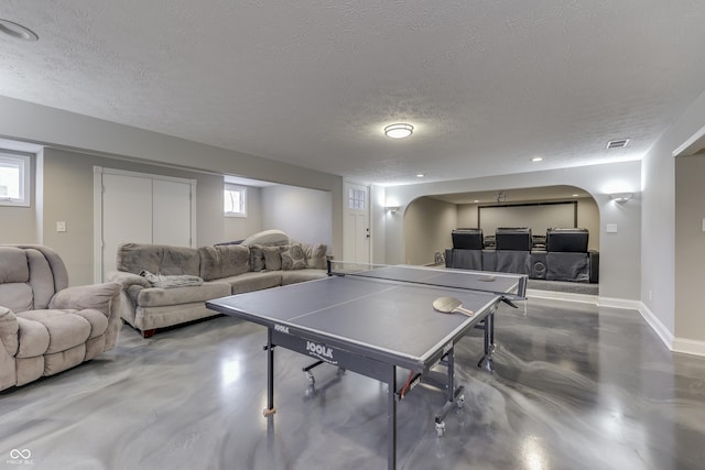 rec room with baseboards, visible vents, arched walkways, concrete flooring, and a textured ceiling