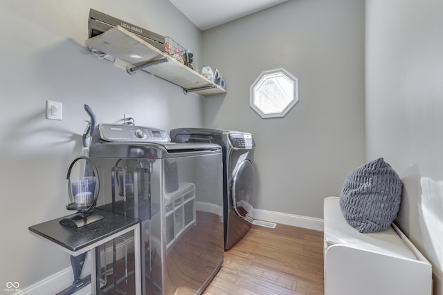 washroom featuring laundry area, wood finished floors, baseboards, and washing machine and clothes dryer