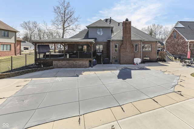 rear view of house with a patio, fence, brick siding, and a chimney