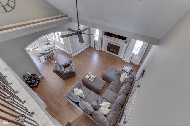 living room with arched walkways, wood finished floors, a ceiling fan, and vaulted ceiling