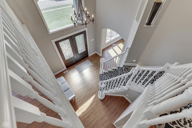 entryway with a high ceiling, a notable chandelier, wood finished floors, and a wealth of natural light