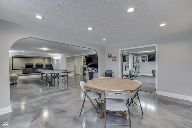 dining room with arched walkways, concrete flooring, and baseboards