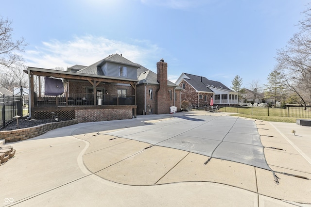 back of house with a patio, fence, a residential view, brick siding, and a chimney