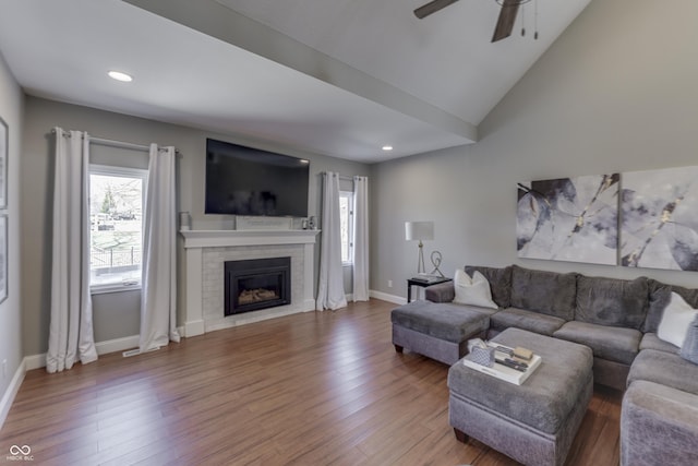 living area featuring a brick fireplace, wood finished floors, and a ceiling fan