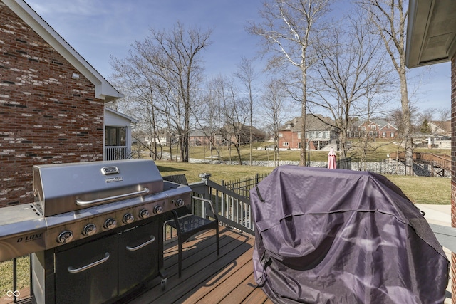 deck featuring area for grilling, fence, a residential view, and a lawn