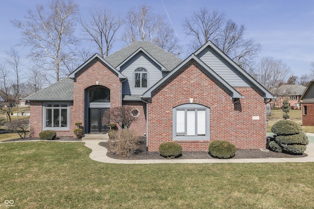 traditional home featuring brick siding, a front lawn, and roof with shingles