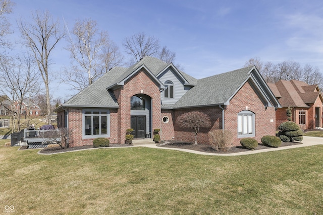 view of front of home featuring brick siding, a shingled roof, and a front yard