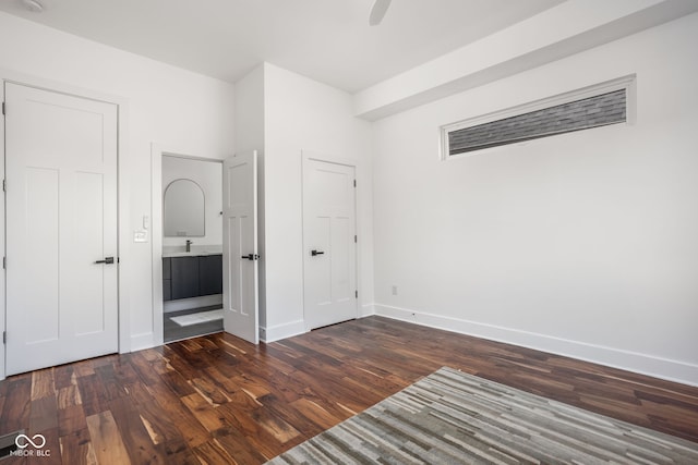 unfurnished bedroom featuring connected bathroom, a ceiling fan, baseboards, and dark wood-style flooring