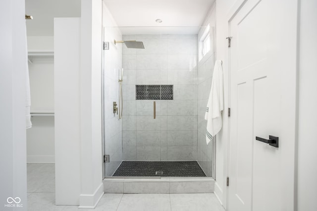 bathroom featuring a spacious closet, tile patterned flooring, and a stall shower