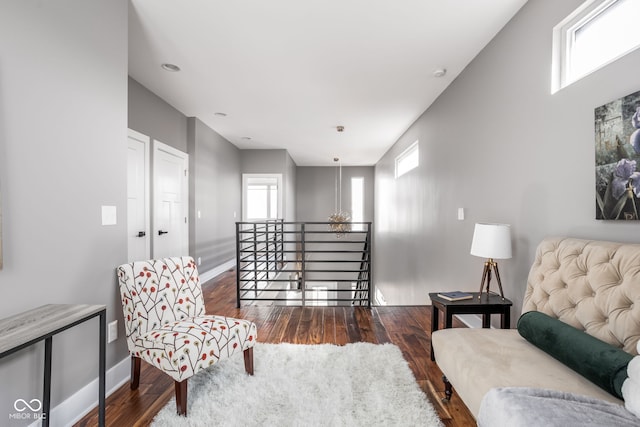 living area with baseboards, an upstairs landing, a healthy amount of sunlight, and wood finished floors